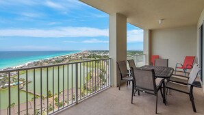 A balcony with a table and chairs, overlooking a coastal view with buildings and a body of water.