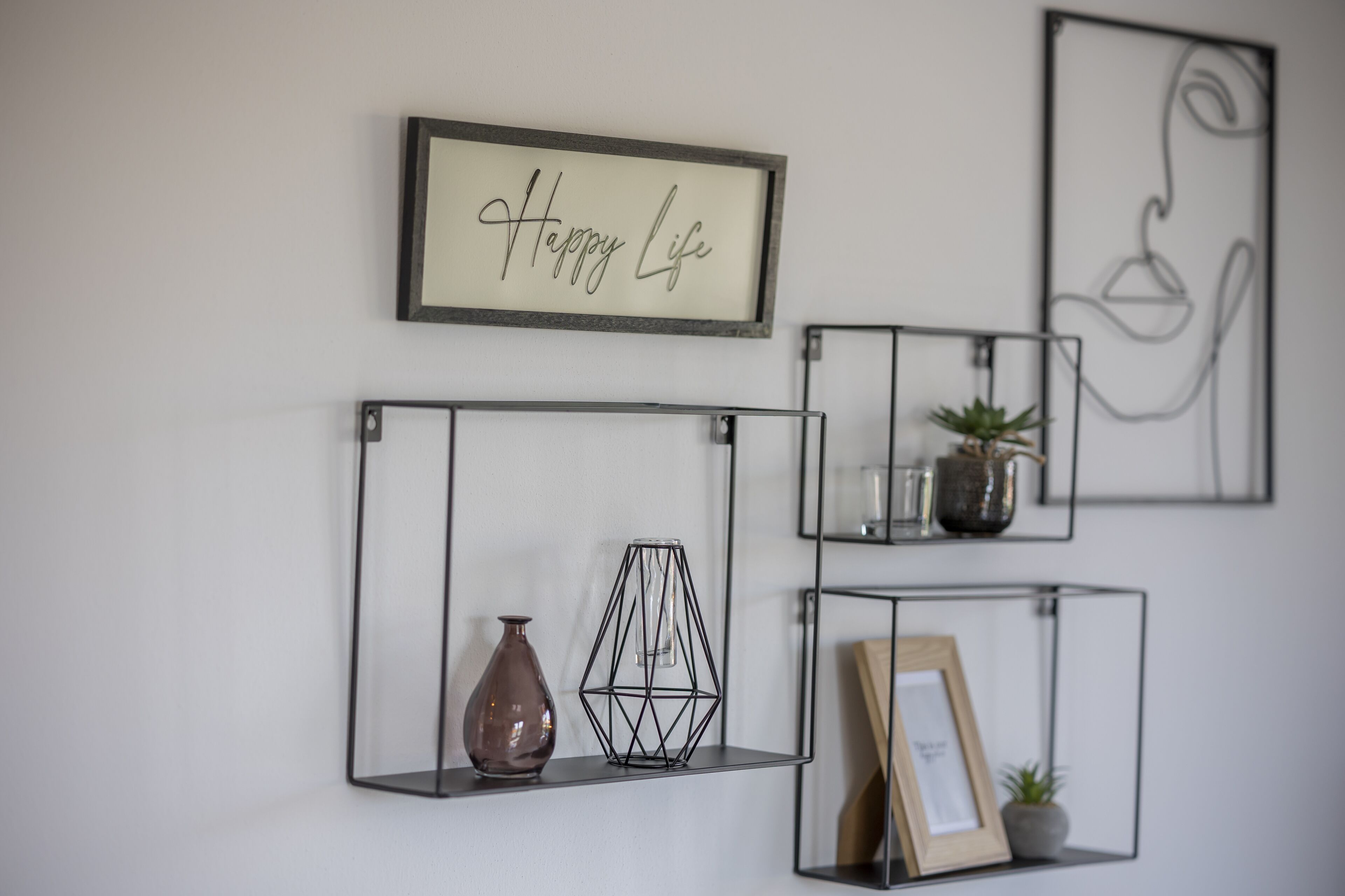 Un mur avec trois étagères en métal, chacune contenant des objets différents.
