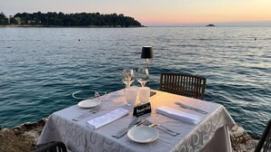 Ein Tisch für zwei, auf dem ein „Reserviert“-Schild steht, mit Blick auf ein ruhiges Meer und eine entfernte Küstenlinie.