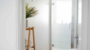 A bathroom with a wooden ladder, a potted plant, a toilet, and a shower area.