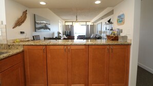 Une cuisine dotée de meubles en bois, de plans de travail en granit et d’un îlot central.