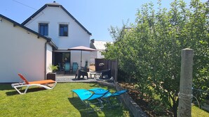 Una casa moderna amb un pati que disposa de mobiliari exterior i un petit jardí.