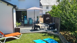A backyard with a patio area, outdoor furniture, and a barbecue grill. - Fully renovated house, garden & terrace 5mn from the beach, underfloor heating (Combrit)