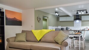 A living room with a sofa, a dining table with chairs, and a kitchen area in the background. - 2 bedroom accommodation in Street (Street)
