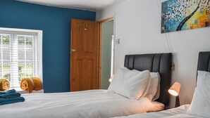 A hotel room with two beds, a wooden door, a window with blinds, and a painting on the wall. - 2 bedroom accommodation in Street (Street)