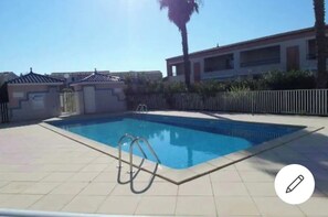 Relax by the pool surrounded by a deck and a white fence, with a ladder for easy access.