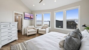 A bedroom with a large bed, a ceiling fan, and a view of the mountains through the windows. - Highland Chateau at Longridge  (Sleeps 34) (Garden City)