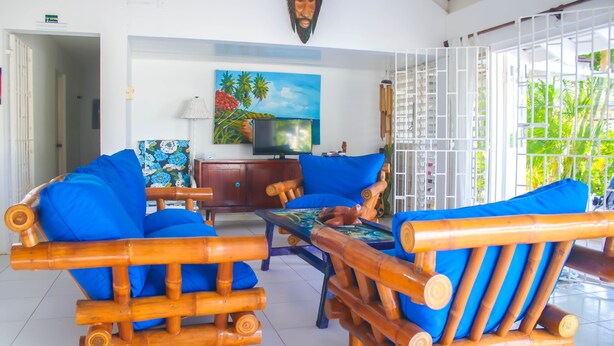 A room with a wooden sofa set, a television, and a painting on the wall. - One Rythm (Duncans)