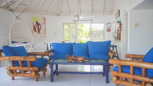 A room with a wooden sofa set, a hanging chair, and a glass-top coffee table. - One Rythm (Duncans)