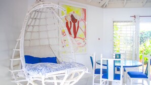 A room with a hanging chair, a table, chairs, and a painting on the wall. - One Rythm (Duncans)