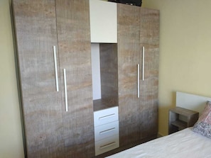 A bedroom with a large wardrobe, a bed, and a small bedside table.