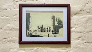 A framed historical photograph of a building with a tower and arches, mounted on a textured wall. - RETRO PALACE (Tashkent)