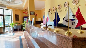 A reception area with a marble counter, flags of various countries, and clocks displaying different times. - RETRO PALACE (Tashkent)