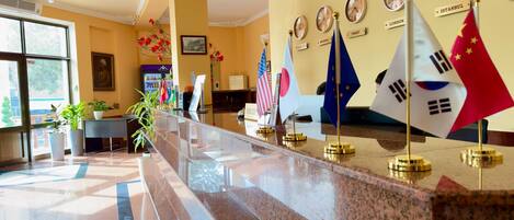 A reception area with a marble counter, flags of various countries, and clocks displaying different times.