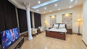 A hotel room with a large bed, a television, a desk, and two lamps. - RETRO PALACE (Tashkent)