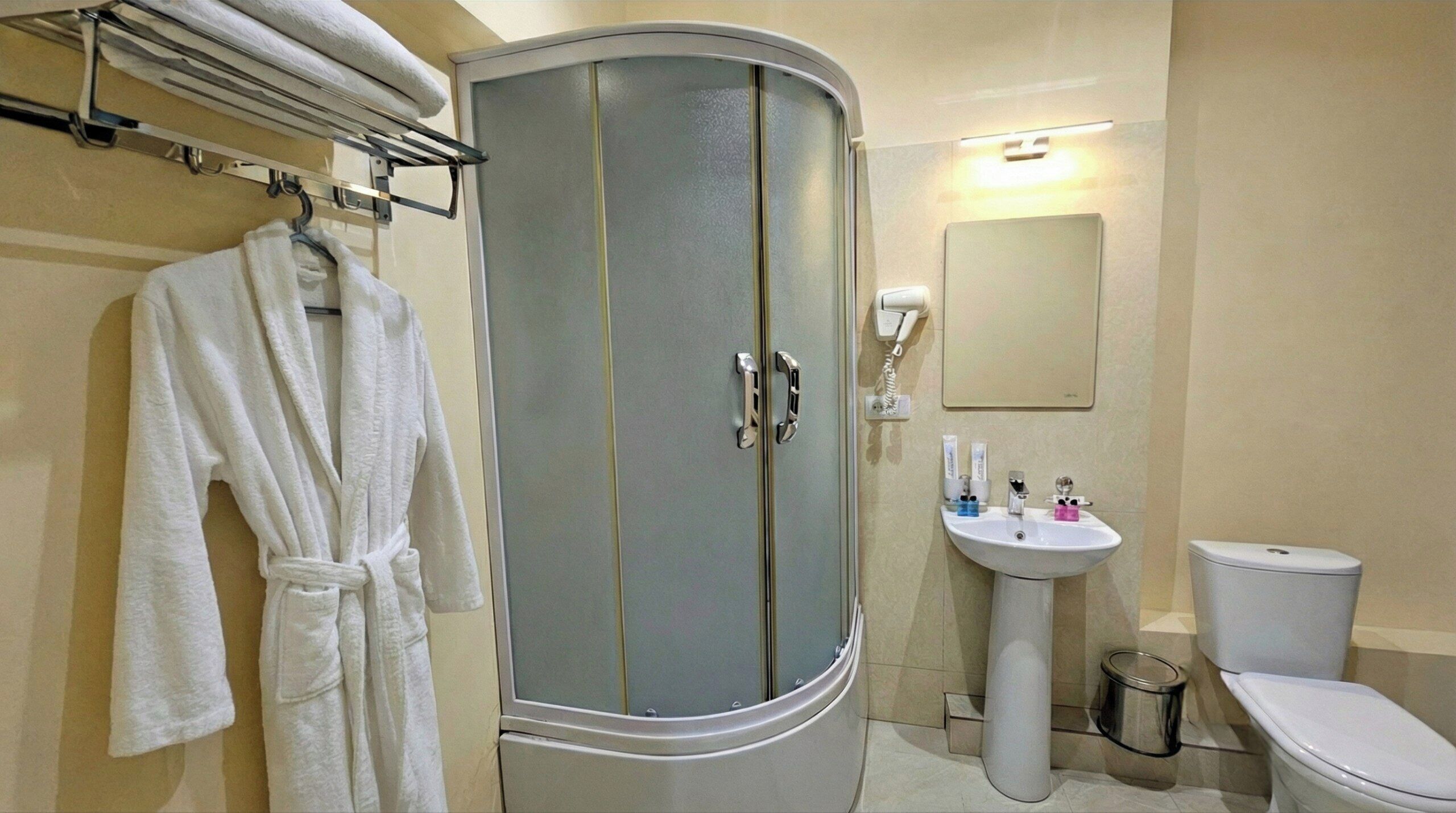 A bathroom with a curved cabinet, a sink, a toilet, and a mirror.