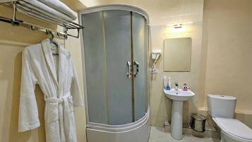 A bathroom with a curved cabinet, a sink, a toilet, and a mirror.