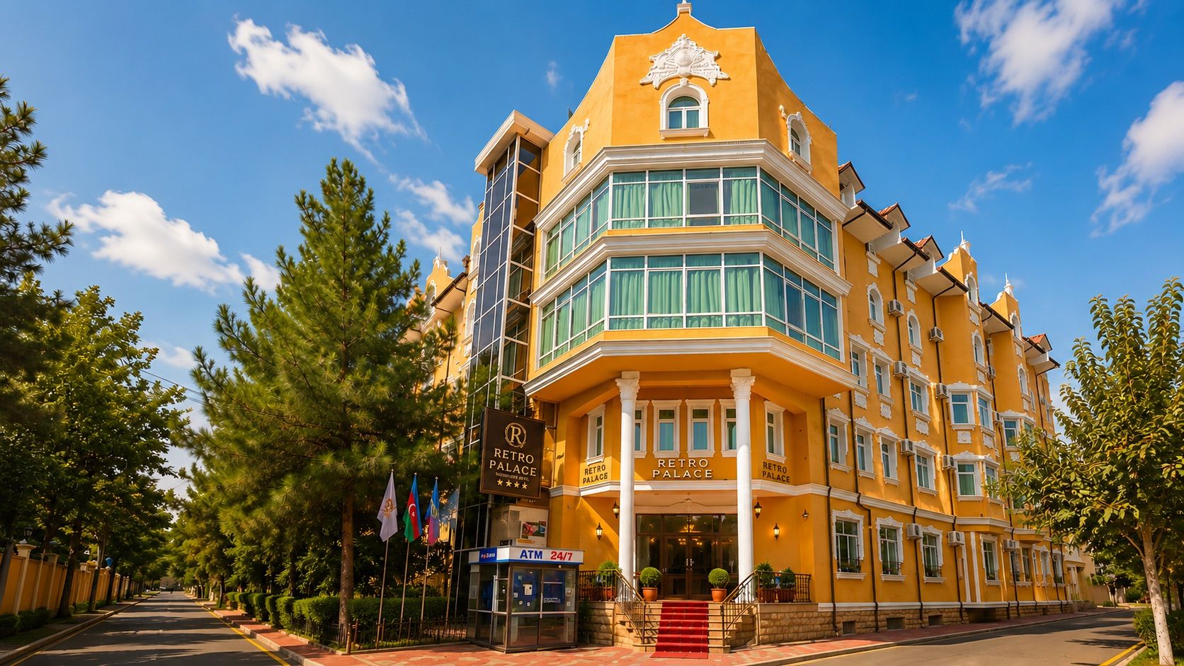Un edificio de varios pisos con una entrada destacada, un cartel que indica que es un hotel y una exhibición de banderas.