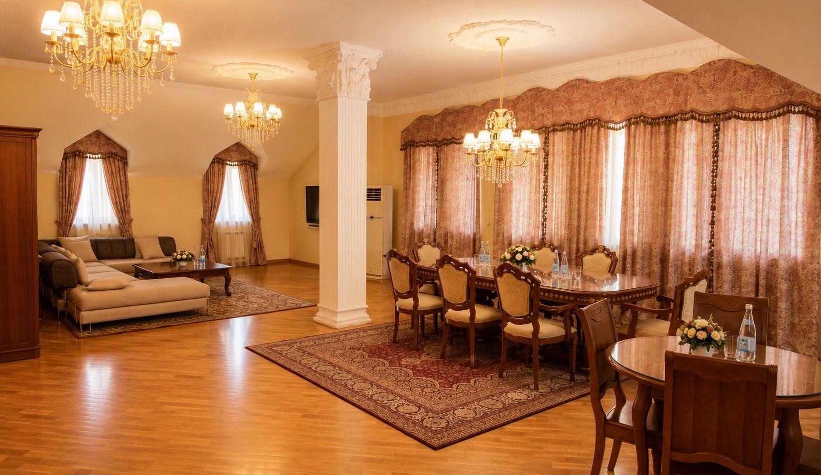 A spacious living room with a sofa, a dining area with a round table and chairs, and a chandelier.