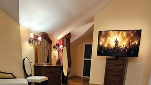 Una habitación de hotel con una cama, un espejo grande, un aparador, un televisor y un cuadro en la pared.