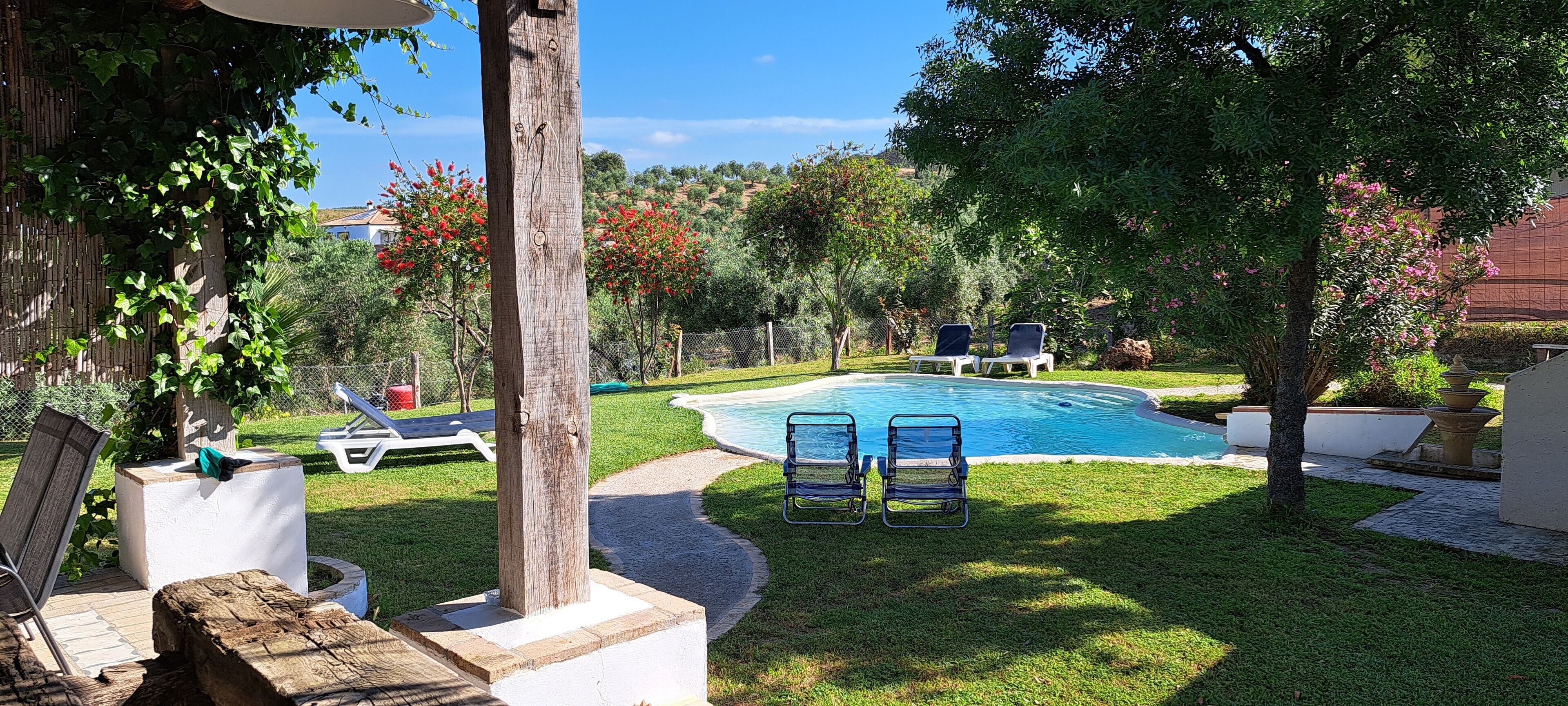 A backyard with a swimming pool, two lounge chairs, and a wooden post.