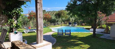 A backyard with a swimming pool, two lounge chairs, and a wooden post.