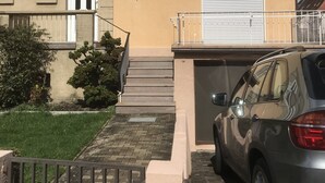 A two-story building with a beige facade, a tiled roof, and a parked car in front. - Doppelhaushälfte mit Garten ca. 130qm (Radolfzell am Bodensee)
