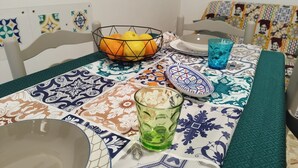 Ett matbord med en mönstrad duk, en skål med frukt, ett glas och en tallrik.