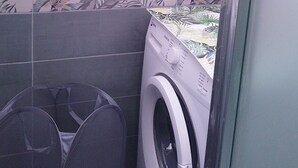 Ett litet utrymme för tvätt med en tvättmaskin och en tvättkorg.