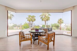 Un vaste balcon doté d’une table ronde et de chaises, offrant une vue sur les palmiers et le paysage urbain.