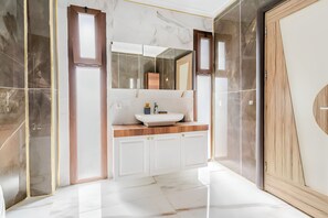 A modern bathroom with a large mirror, a white sink, and marble flooring. - Salida Inn (Kusadasi)