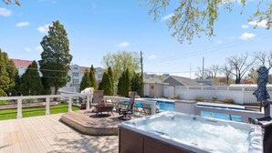 A backyard with a hot tub, a pool, and outdoor seating.