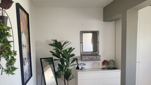 Una habitación con un aparador blanco, un espejo y dos plantas en macetas.
