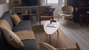 Una sala de estar con sofá, sillones, una mesa de centro, televisor y vista al agua.