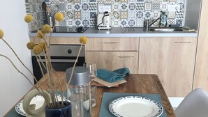 Una mesa de madera con un plato, un florero con flores secas, una botella de agua y un vaso.