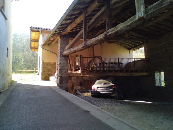 A narrow road leading to a building with a stone facade and wooden beams. A car is parked in front of the building. - Renovated farmhouse in a hamlet in the Monts du Lyonnais (Courzieu)