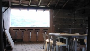 Un'accogliente stanza in legno con pavimento in legno, un tavolo rotondo e quattro sgabelli da bar.