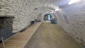An interior with a stone wall, wooden benches, and a gravel floor. - Renovated farmhouse in a hamlet in the Monts du Lyonnais (Courzieu)