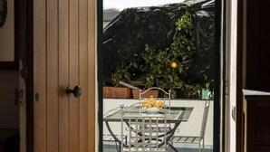 Eine offene Tür führt zu einer Terrasse mit Tisch und Stühlen, einem Fahrrad und einem Blumentopf.
