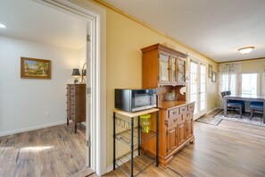 Kitchen area with a wooden cabinet, microwave, and table with a lamp.