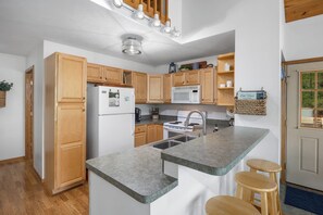 A kitchen with wooden cabinets, a built-in microwave, a stainless steel sink, and a granite countertop.