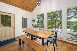 Un coin repas avec une table en bois, des chaises et un banc. Une plante en pot est posée sur la table.