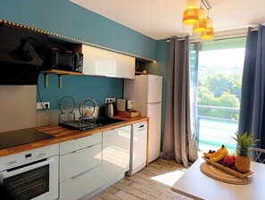 A modern kitchen with a built-in oven, a refrigerator, and a dining area with a table set for a meal.