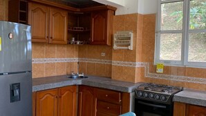 Una cocina con armarios de madera, un refrigerador de acero inoxidable, una estufa a gas y un lavamanos.