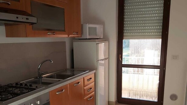 Una cocina con armarios de madera, una estufa a gas, un microondas y un refrigerador.