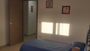 Una habitación con dos camas, una mesita y una puerta que da a otra estancia.