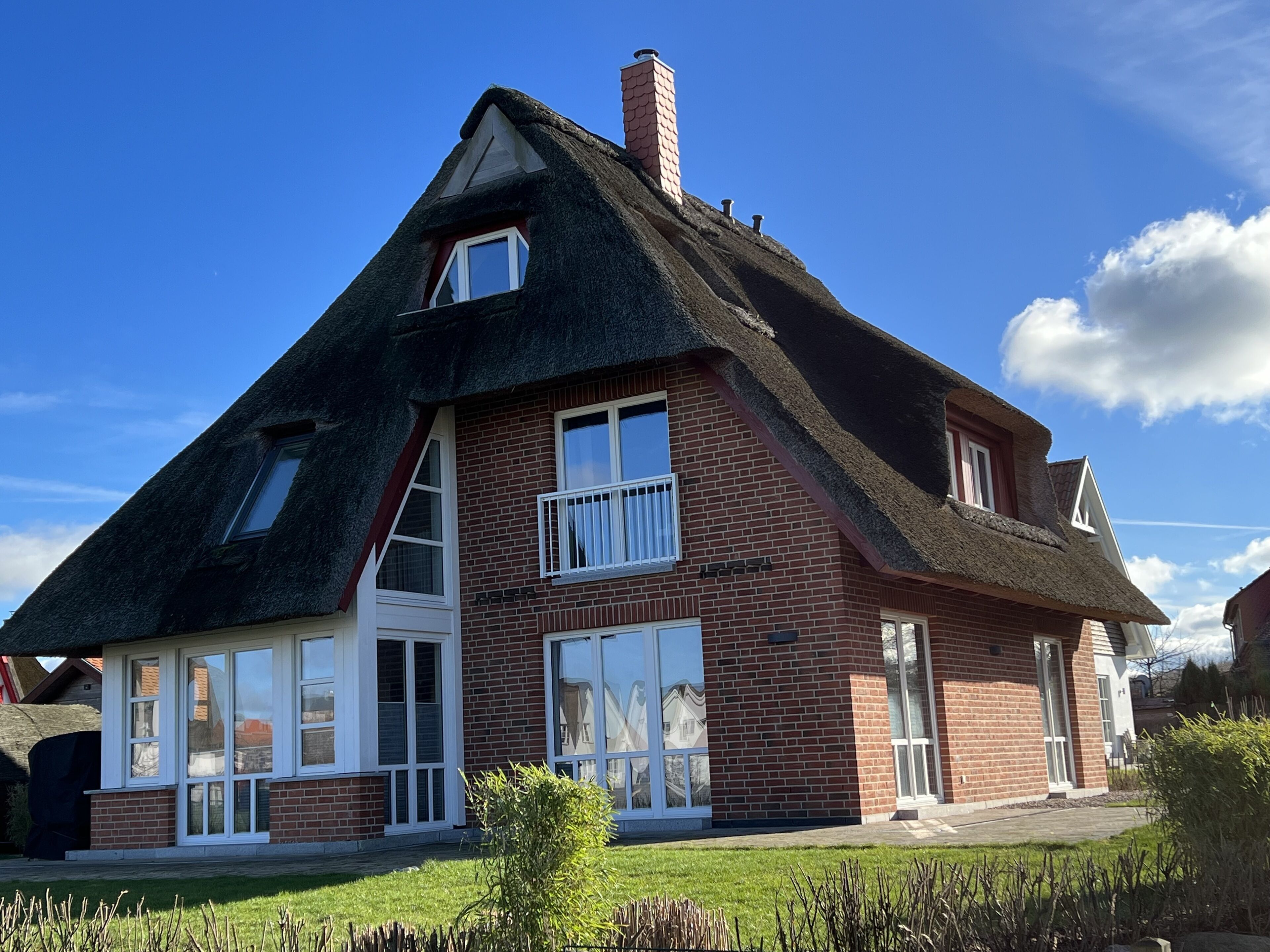 A house with a steeply pitched roof, large windows, and a brick facade.