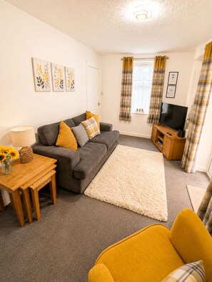 A living room with a sofa, a coffee table, a TV stand, and a rug.