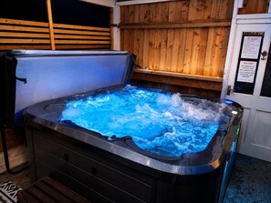 A hot tub with a wooden wall and a sign about hot tub rules. - Synod Cottage | Private Hot Tub, Dog Friendly, Near New Quay (Ceredigion)