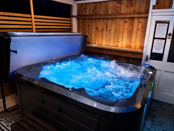A hot tub with a wooden wall and a sign about hot tub rules. - Synod Cottage | Private Hot Tub, Dog Friendly, Near New Quay (Ceredigion)